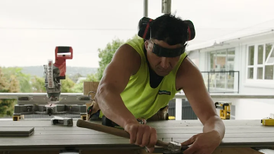 Worker using tools to measure and cut a piece of wood